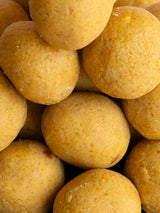 Freshly roasted gram flour Besan Ladoo balls, an authentic Indian mithai made with premium ghee and no preservatives.
